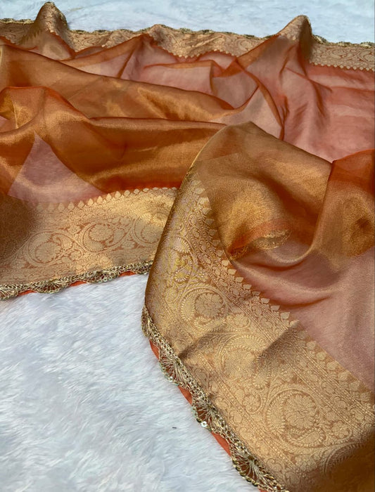 Peach tissue saree with gold zari pallu section and decorative edge trim.