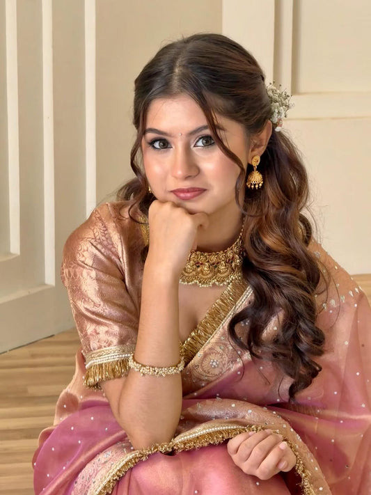 Blush pink tissue saree with gold border, ornate blouse, and dotted pallu