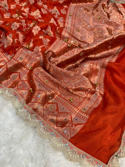 Coral-red silk saree with detailed printed motifs and silver-gold embellished border