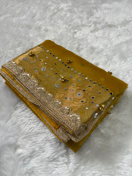 Folded gold tissue saree with ornate silver border and scattered sequin motifs
