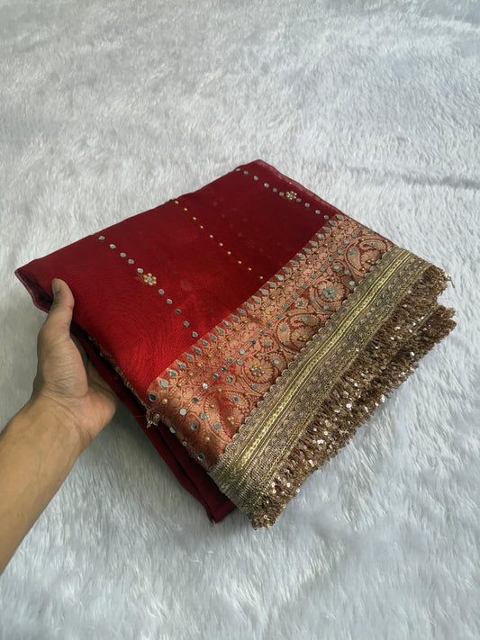 Red saree folded with gold-trim border and tan motif pallu end