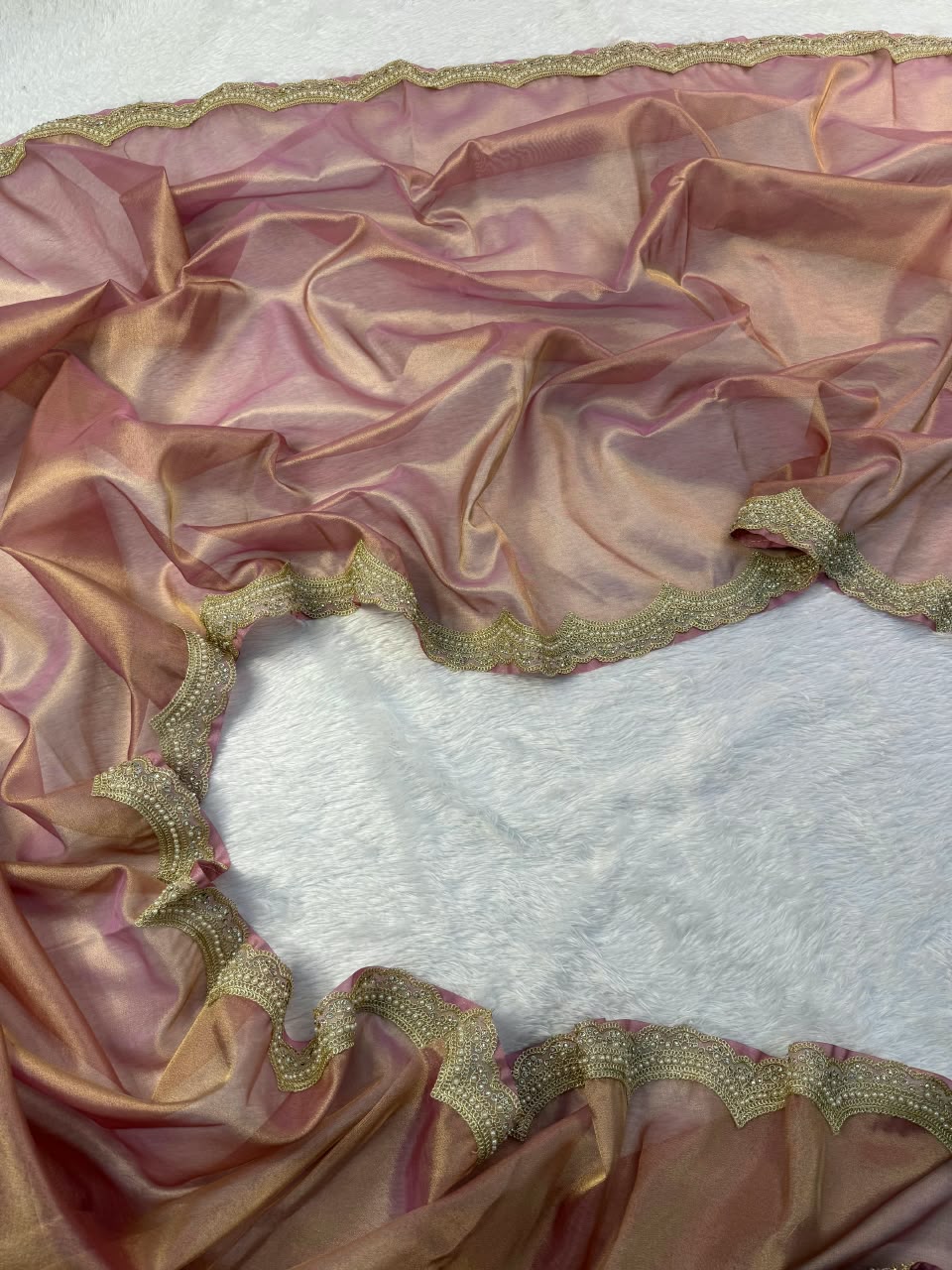Mauve tissue saree with scalloped gold embroidered border, spread flat on base