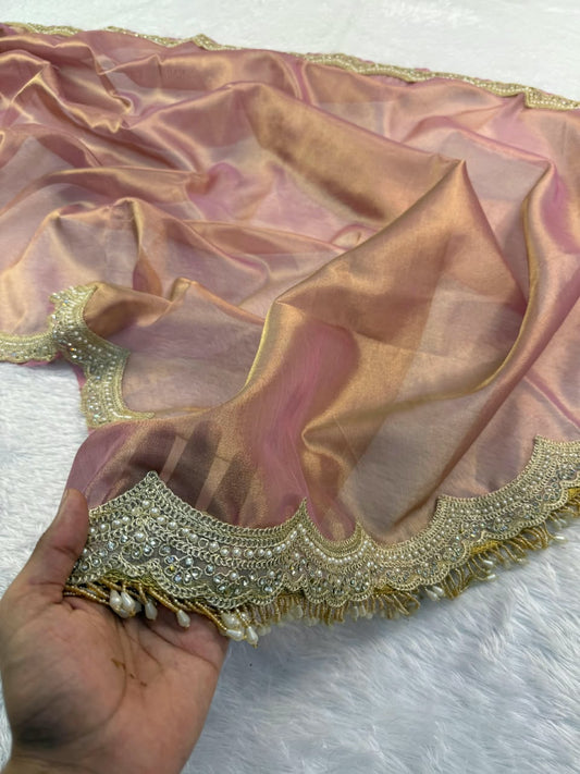 Hand holding mauve tissue saree with scalloped gold embroidered border and sheen