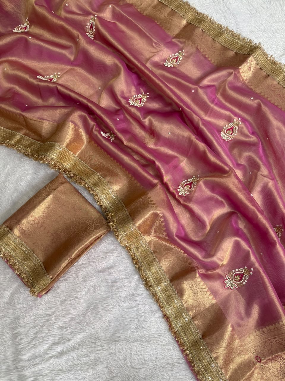 Pink tissue saree with gold zari border and small embroidered motifs, folded