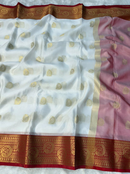 White tapeta saree laid flat with gold motifs, pink side panel, and red-gold border